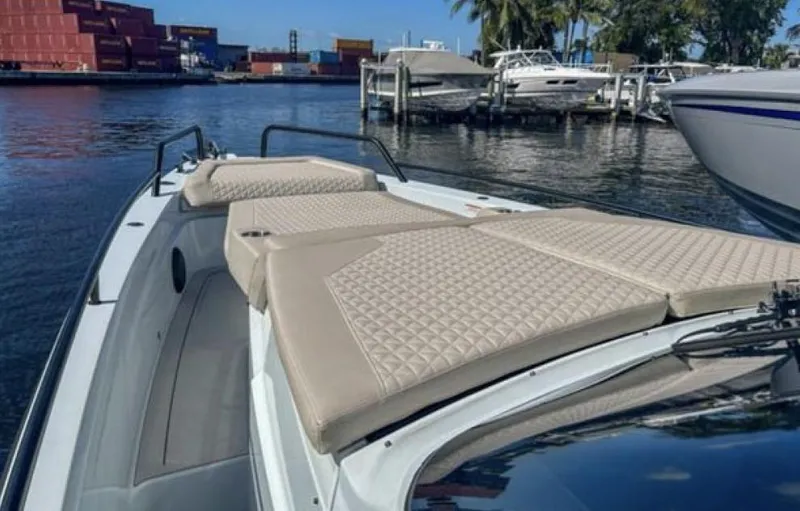Kraken Yacht Photos Pics 2023 BRABUS Shadow 900 boat with beige cushioned seating, docked near other boats.
