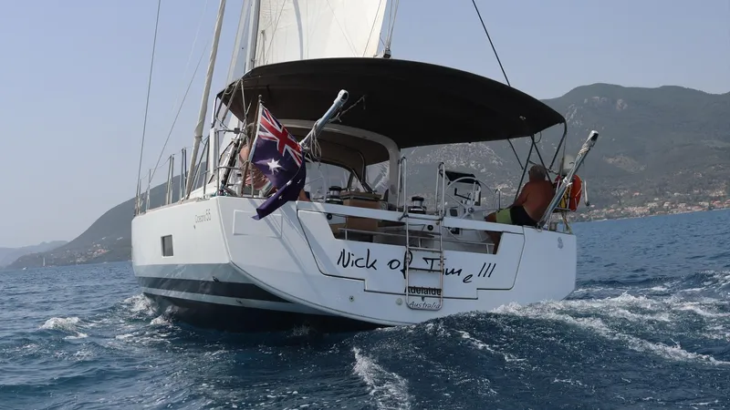 Nick Of Time III Yacht Photos Pics Sailing yacht Beneteau Oceanis 55, 2015 model, cruising on open water with flags displayed.