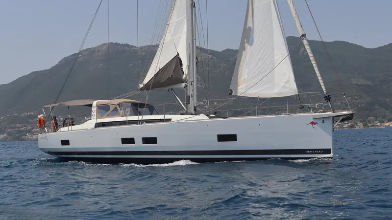 Nick Of Time III Yacht Photos Pics 2015 Beneteau Oceanis 55 sailing yacht on open water with mountainous backdrop.