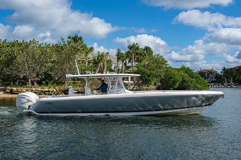  Yacht Photos Pics 2019 Intrepid 407 Nomad FE boat cruising on a sunny day near lush greenery.