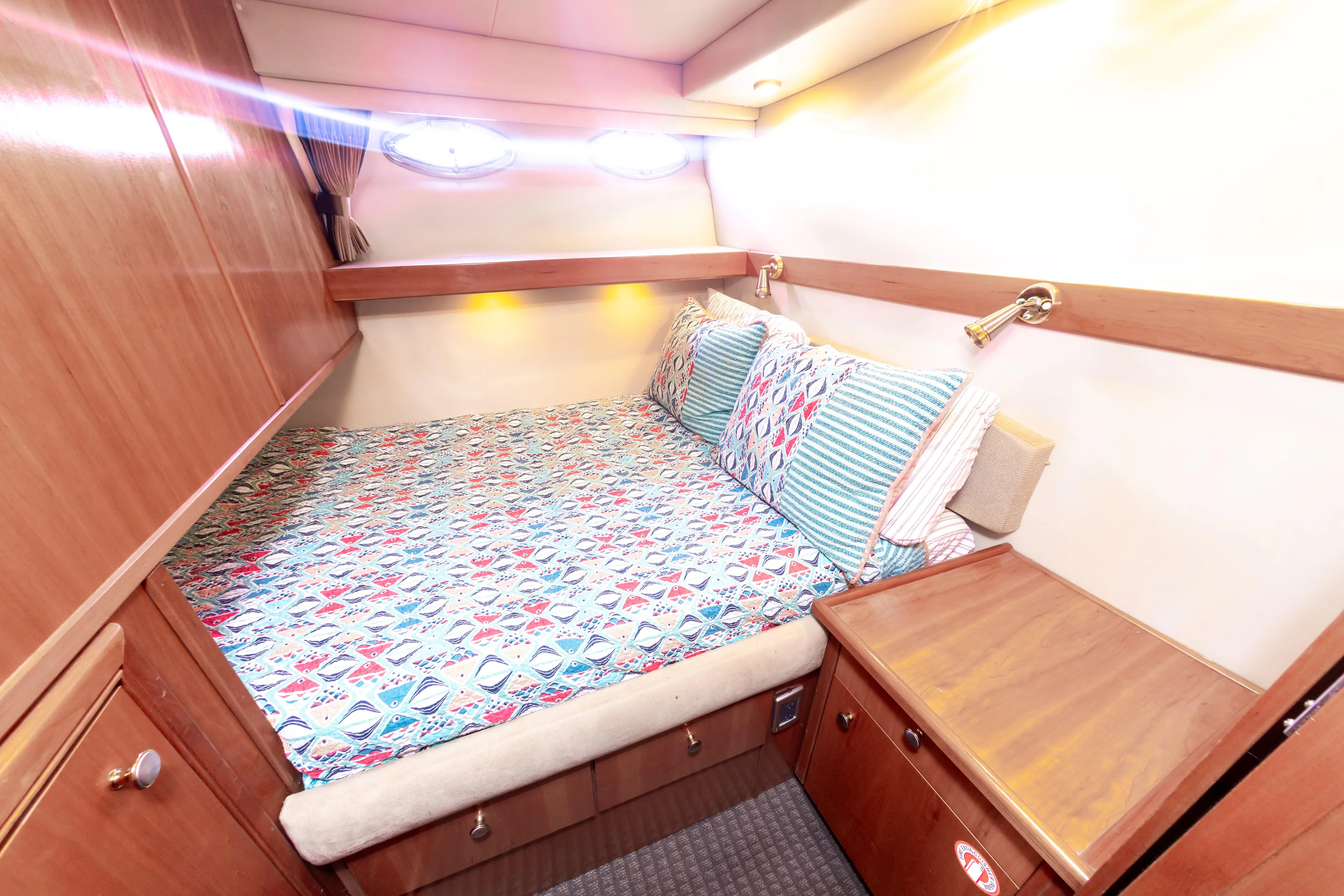 Adventures Await Yacht Photos Pics Cozy cabin interior of 2004 Meridian 490 Pilothouse with colorful bedding and wooden furnishings.