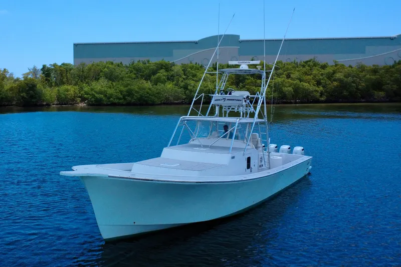Highly Migratory Yacht Photos Pics 2017 Chesapeake 53 Center Console boat on calm water near greenery.