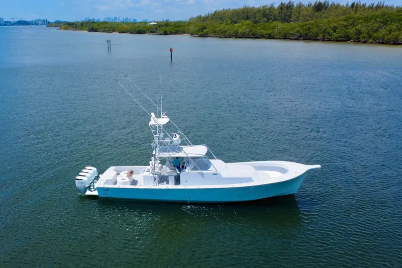 Highly Migratory Yacht Photos Pics 2017 Chesapeake 53 Center Console boat on calm water, surrounded by lush greenery.