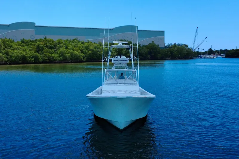 Highly Migratory Yacht Photos Pics 2017 Chesapeake 53 Center Console boat on calm water, surrounded by greenery and industrial buildings.