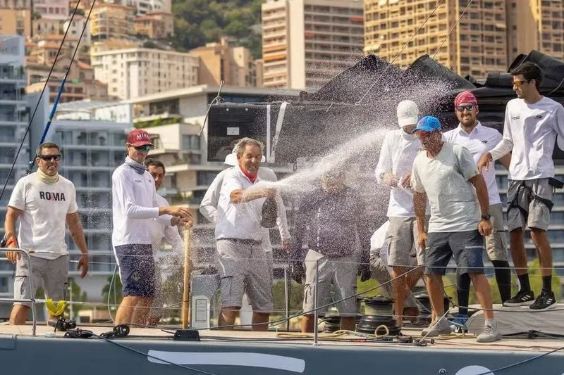 Manticore Yacht Photos Pics Crew celebrating on a 2019 Mylius 60 yacht, spraying champagne on deck.
