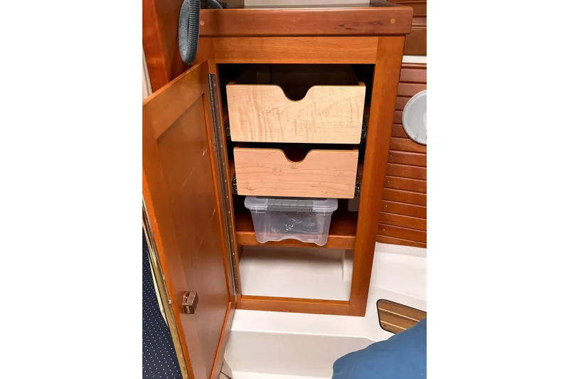  Yacht Photos Pics Wooden cabinet with open door, revealing two drawers and a plastic container inside a 2013 Back Cove 34.
