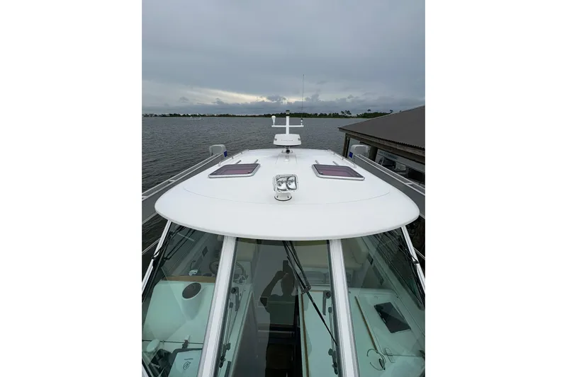  Yacht Photos Pics 2013 Back Cove 34 boat on water, overcast sky, docked near a pier.