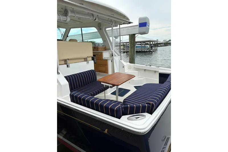  Yacht Photos Pics 2013 Back Cove 34 boat with striped seating and wooden table, docked by the water.