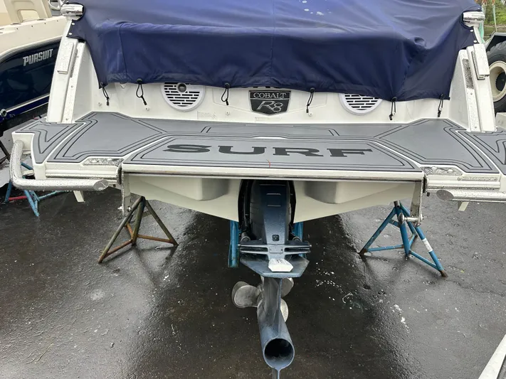  Yacht Photos Pics 2022 Cobalt R8 Surf boat rear view with covered deck and visible propeller.