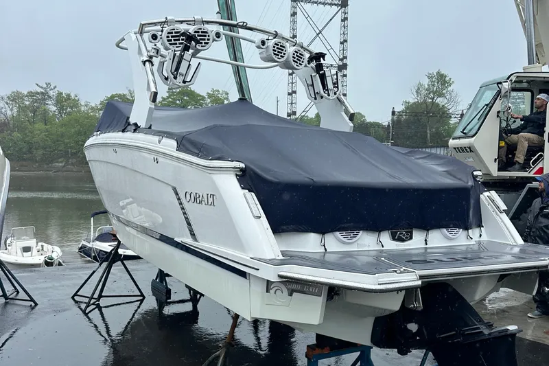  Yacht Photos Pics 2022 Cobalt R8 Surf boat covered, docked near water on a rainy day.