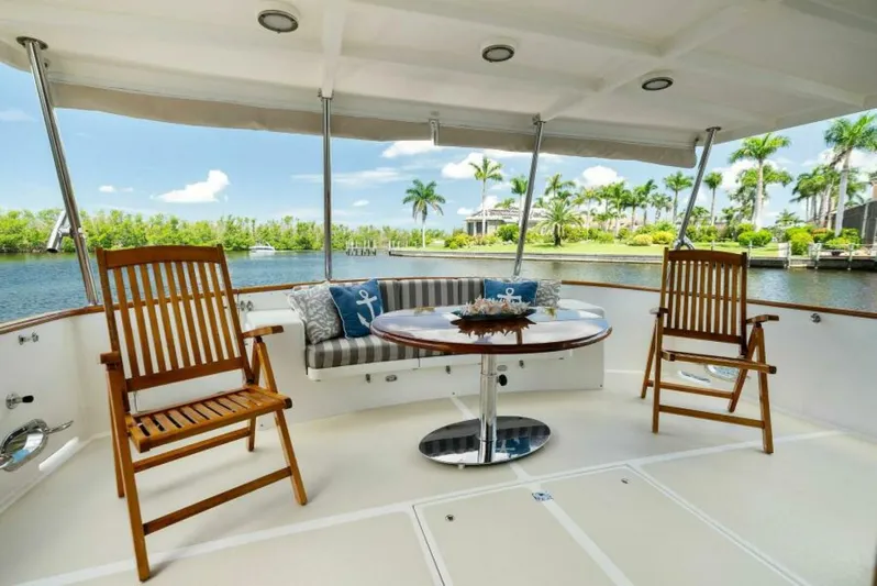 Orion II Yacht Photos Pics Luxurious 2001 Grand Alaskan 64 pilot house yacht deck with chairs and table, scenic waterfront view.