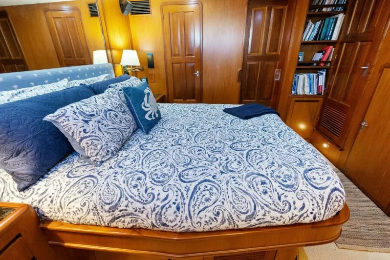 Orion II Yacht Photos Pics Luxurious bedroom in 2001 Grand Alaskan 64 Pilot House yacht with elegant bedding and wooden cabinetry.