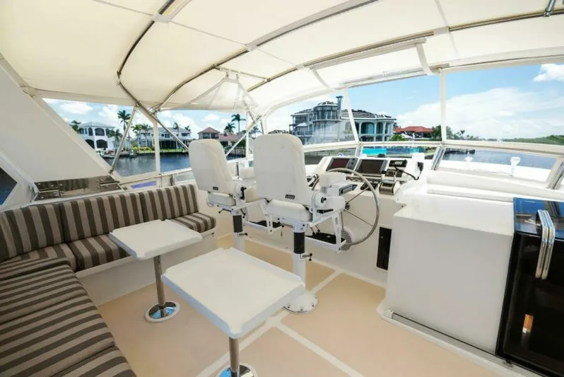 Orion II Yacht Photos Pics Luxurious 2001 Grand Alaskan 64 pilot house interior with seating and helm, overlooking waterfront homes.
