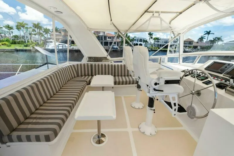 Orion II Yacht Photos Pics 2001 Grand Alaskan 64 Pilot House interior with striped seating and helm, docked by waterfront homes.