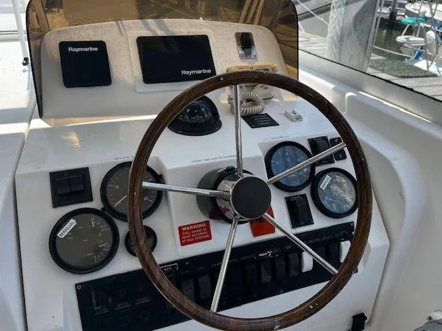  Yacht Photos Pics 2003 Mainship Pilot 34 helm with Raymarine electronics and classic wooden steering wheel.
