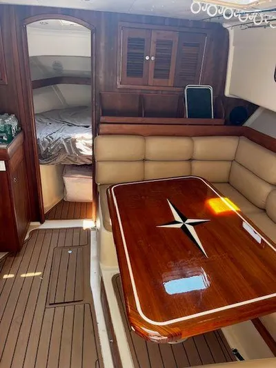  Yacht Photos Pics 2003 Mainship Pilot 34 interior with wood table, cushioned seating, and cozy sleeping area.
