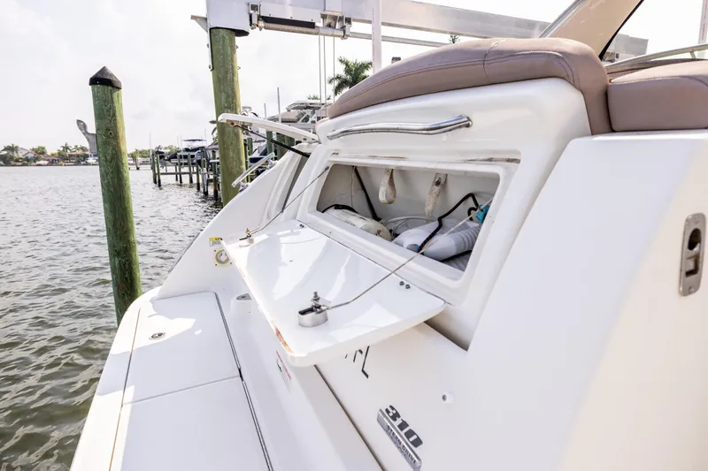  Yacht Photos Pics 2016 Sea Ray 310 Sundancer boat with open storage compartment, docked by the water.