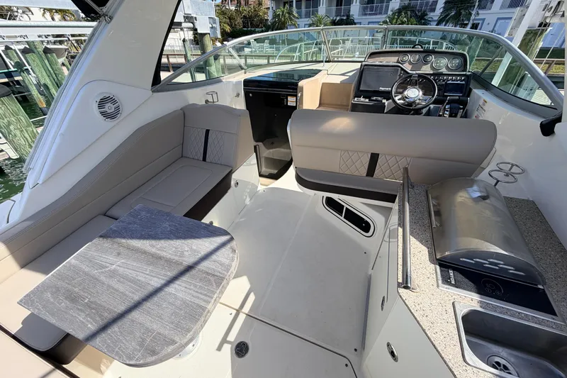  Yacht Photos Pics 2016 Sea Ray Sundancer 310 cockpit with seating, table, and helm controls.