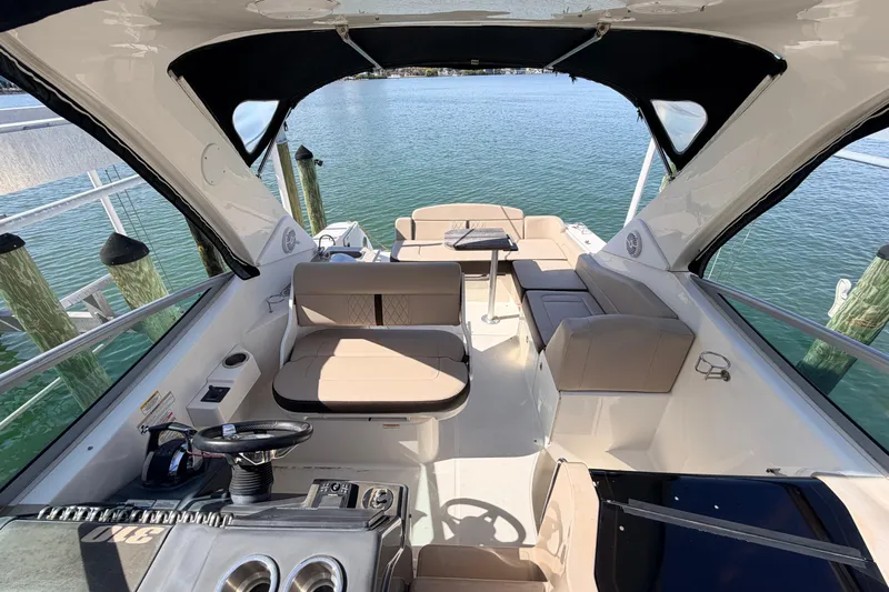  Yacht Photos Pics 2016 Sea Ray Sundancer 310 boat interior with seating and helm, docked by the water.