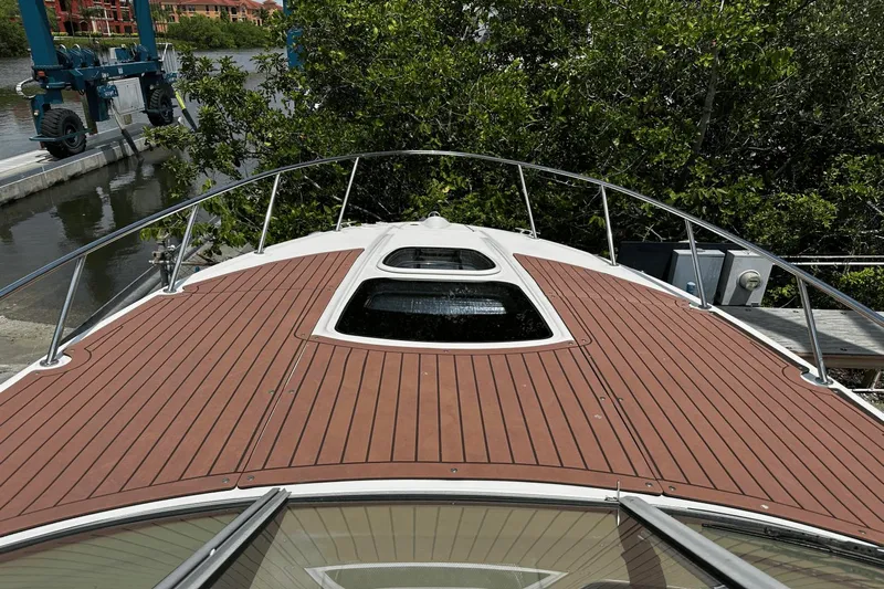 Parce Yacht Photos Pics 2016 Sea Ray 310 Sundancer boat deck with wood finish, docked near lush greenery.