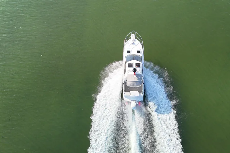  Yacht Photos Pics Aerial view of 2026 Solara S-250 Coupe boat cruising on green water.