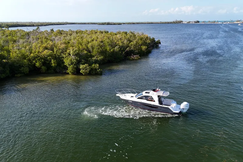  Yacht Photos Pics 2026 Solara S-250 Coupe cruising on a scenic river near lush greenery.