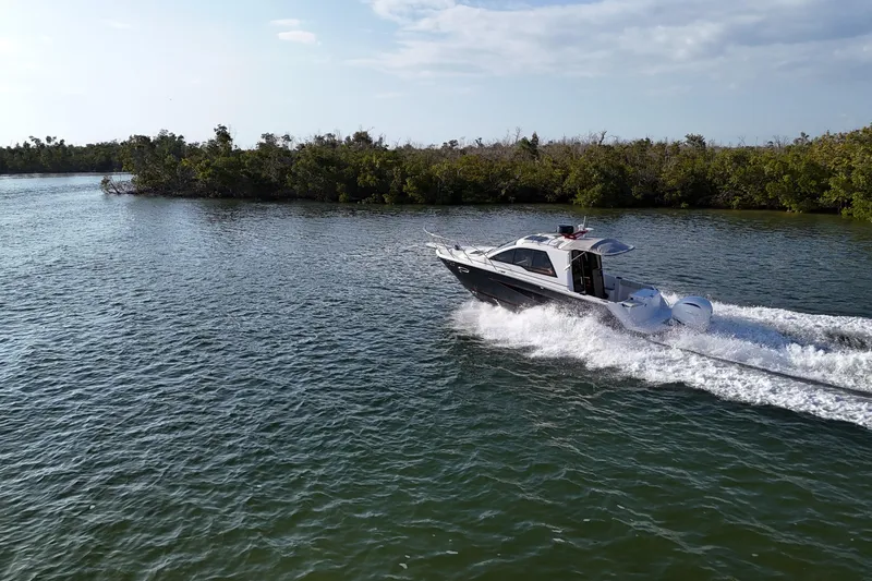  Yacht Photos Pics 2026 Solara S-250 Coupe cruising on a scenic waterway with lush greenery.