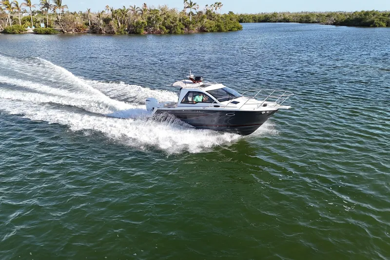  Yacht Photos Pics 2026 Solara S-250 Coupe cruising on a scenic lake with lush greenery.