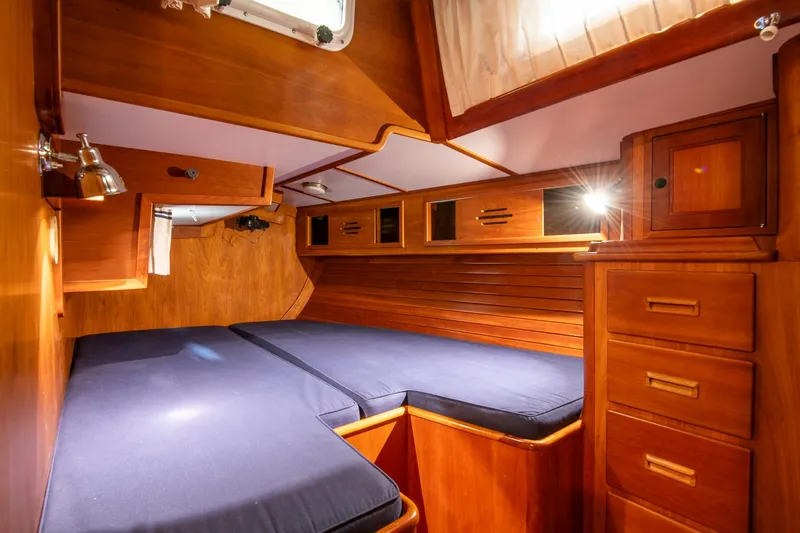 Regulus Yacht Photos Pics Cozy cabin interior of 1993 Hinckley Sou'wester 51 with wooden furnishings and blue bedding.
