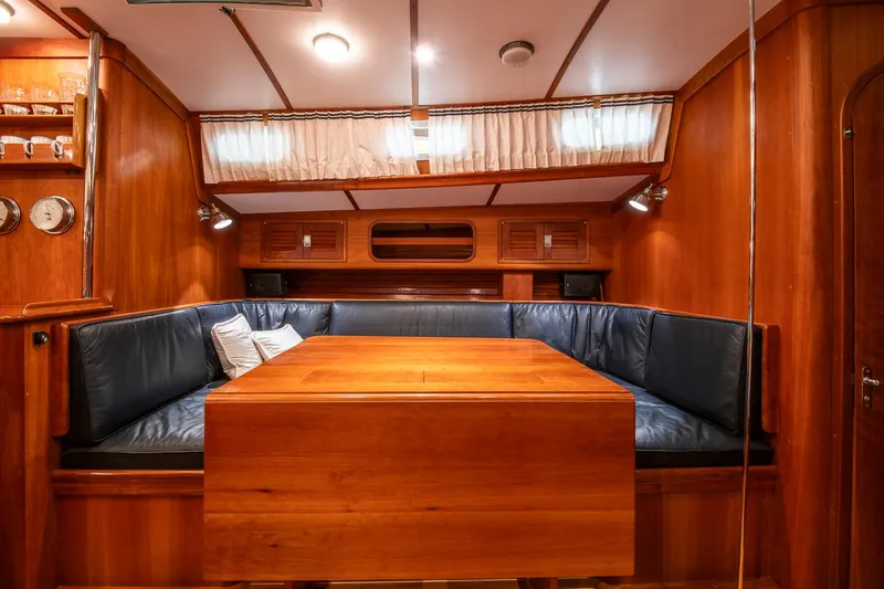 Regulus Yacht Photos Pics Interior of 1993 Hinckley Sou'wester 51 yacht with wooden dining area and blue seating.