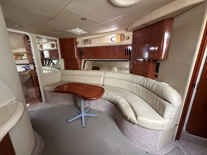  Yacht Photos Pics Luxurious interior of 2000 Sea Ray 410 Sundancer yacht with curved seating and wooden table.