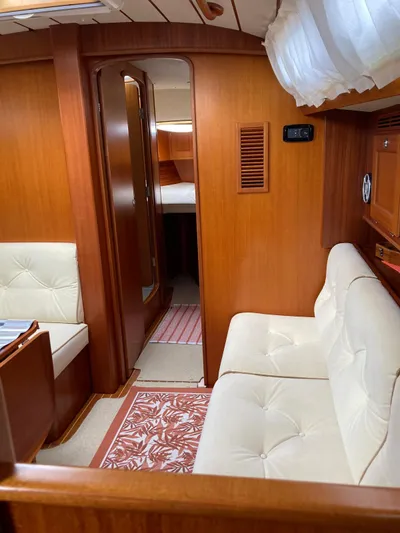 Morgan's Moon Yacht Photos Pics Interior of 2008 Hallberg-Rassy 43 yacht with wood paneling and white cushioned seating.