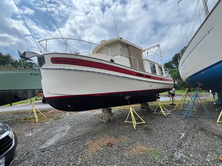 Charley's Tern Yacht Photos Pics 1998 Nordic Tug 32 boat on stands, named "Charley's Tern," under cloudy sky.