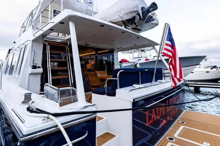  Yacht Photos Pics 2000 Pacific Mariner 65 Motoryacht docked, featuring American flag and elegant seating area.