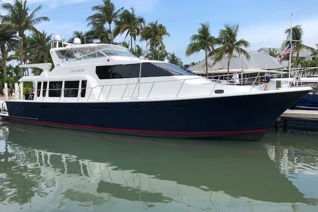  Yacht Photos Pics 2000 Pacific Mariner 65 Motoryacht docked, surrounded by palm trees and calm water.