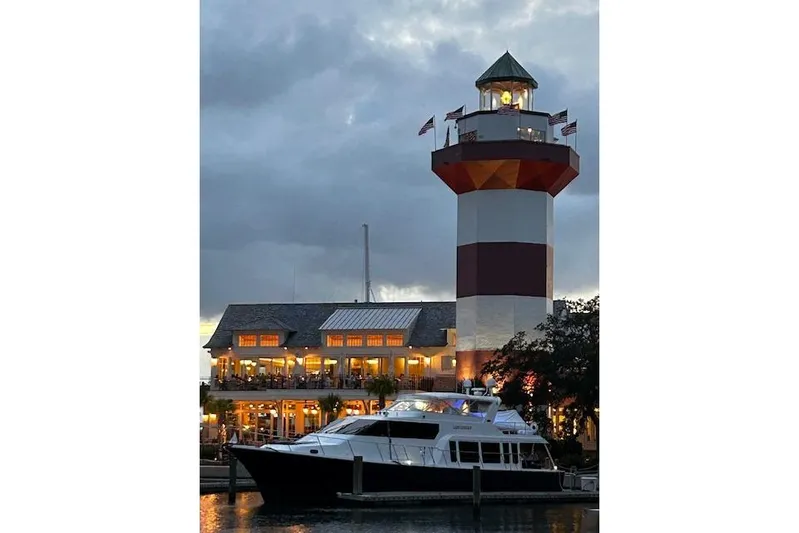  Yacht Photos Pics 2000 Pacific Mariner 65 Motoryacht docked near illuminated lighthouse at dusk.