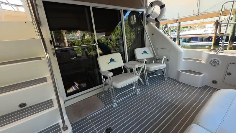Livin' The Dream Yacht Photos Pics 2001 Sea Ray 450 Express Bridge yacht deck with chairs and stairs, docked by water.