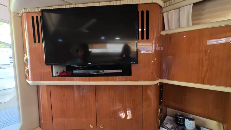 Livin' The Dream Yacht Photos Pics Interior of 2001 Sea Ray 450 Express Bridge with mounted TV and wooden cabinetry.