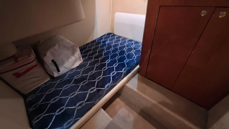 Livin' The Dream Yacht Photos Pics 2001 Sea Ray 450 Express Bridge cabin with blue patterned bedding and wooden storage.