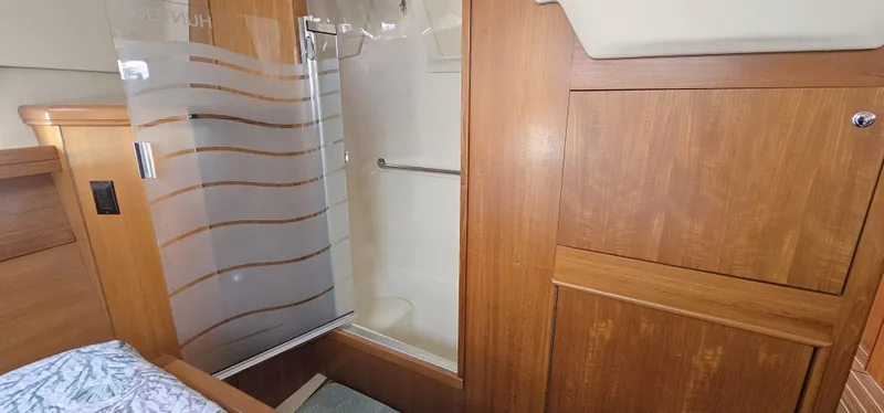  Yacht Photos Pics 2005 Hunter 456 yacht interior with wooden cabinetry and frosted glass shower.