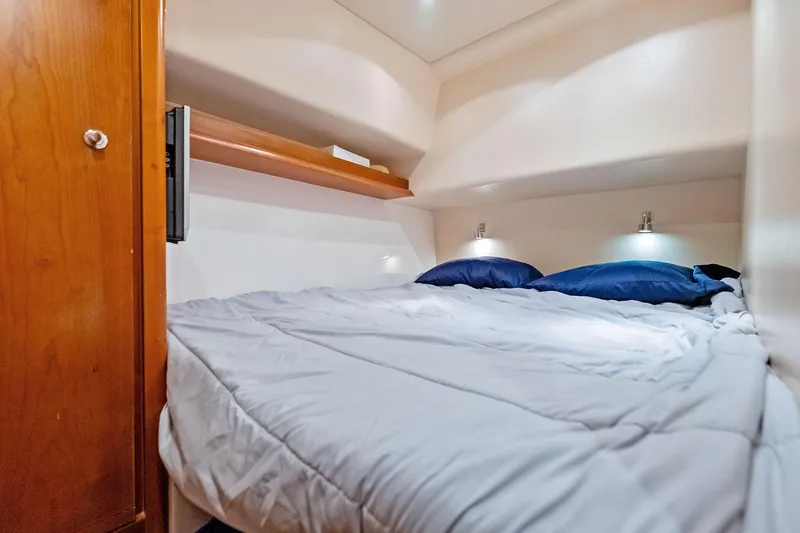 Mr. Bond Yacht Photos Pics Cozy cabin bedroom in 2006 Bertram 39 Convertible yacht with wooden accents and soft lighting.