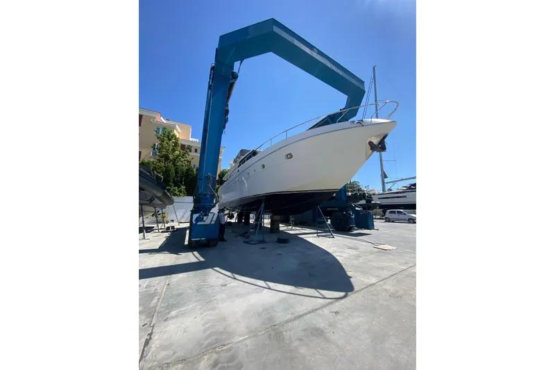  Yacht Photos Pics Sanlorenzo SL62 yacht from 2011 in dry dock, supported by a large blue crane.