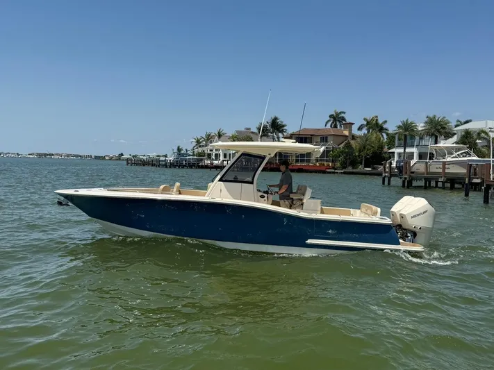  Yacht Photos Pics 2023 Scout 277 LXF boat cruising on a sunny day near waterfront homes.