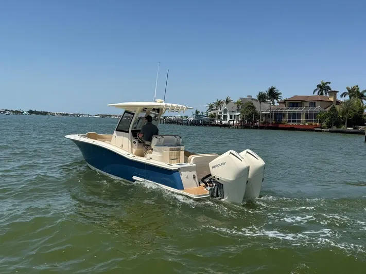  Yacht Photos Pics 2023 Scout 277 LXF boat cruising on a sunny day near waterfront homes.