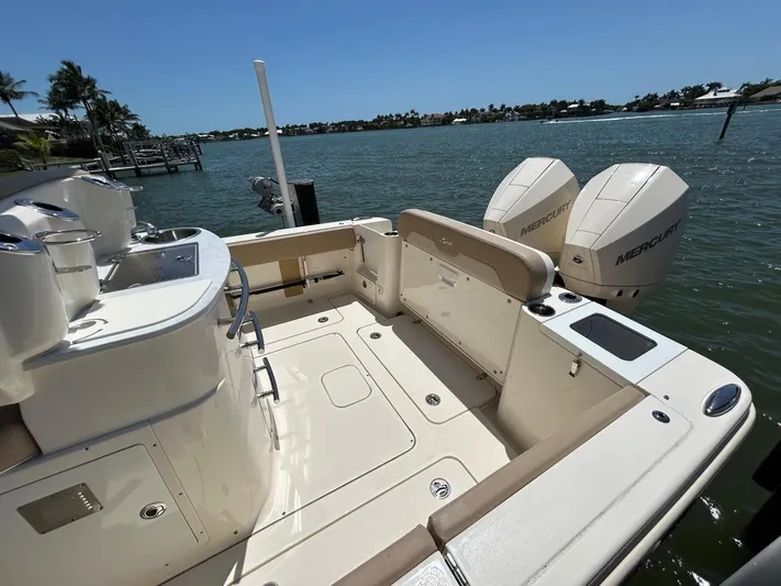  Yacht Photos Pics 2023 Scout 277 LXF boat with dual Mercury engines, docked by a scenic waterfront.