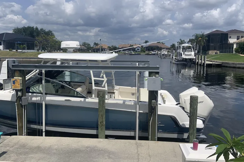  Yacht Photos Pics 2019 Boston Whaler 270 Vantage docked by a canal under cloudy skies.