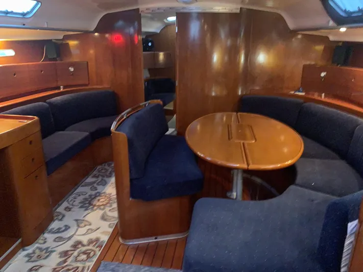 Ayla Yacht Photos Pics Interior of a 1991 Beneteau First yacht with wooden furnishings and blue seating.