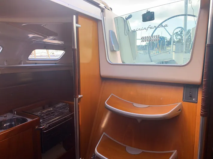 Ayla Yacht Photos Pics Interior view of 1991 Beneteau First sailboat, featuring wooden steps and compact kitchen area.