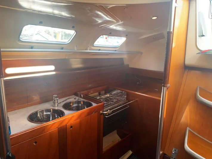Ayla Yacht Photos Pics Interior of 1991 Beneteau First sailboat, featuring a compact wooden kitchen with dual sinks.