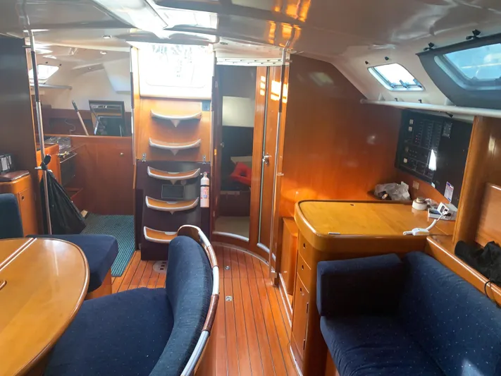 Ayla Yacht Photos Pics Interior of a 1991 Beneteau First sailboat with wooden furnishings and blue seating.